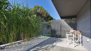 Un patio moderno al aire libre con terraza de madera, un conjunto de asientos y un cerramiento de bambú.