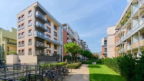 A residential building with multiple balconies, a paved pathway, and bicycles parked along the side. - Sunny Apartment | Balcony | Parking | Workspace. (Wrocław)
