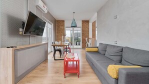A modern living room with a grey sofa, a red coffee table, and a TV mounted on the wall. - Sunny Apartment | Balcony | Parking | Workspace. (Wrocław)