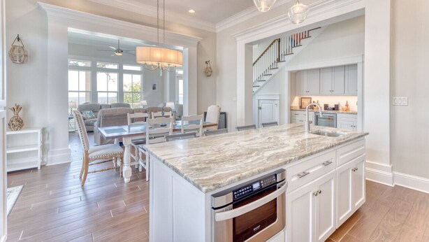 A spacious kitchen with a central island, built-in appliances, and a staircase leading to an upper level. - Gulfport's Premier Beachfront Getaway, Ocean View Beach House! Sleeps 10 (Gulfport)