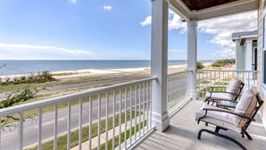A covered porch with a view of the beach, two chairs, and a railing. - Gulfport's Premier Beachfront Getaway, Ocean View Beach House! Sleeps 10 (Gulfport)