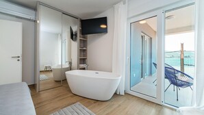 A modern bathroom with a freestanding bathtub, a glass shower enclosure, and a TV mounted above the bathtub. - Stunning home in Zadar, Pasman (Zadar, Pasman)