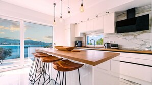 A modern kitchen with a large island, bar stools, and a view of a lake. - Stunning home in Zadar, Pasman (Zadar, Pasman)