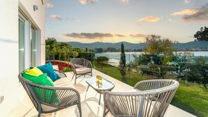 A balcony with wicker furniture, a glass table, and a view of a lake and hills. - Stunning home in Zadar, Pasman (Zadar, Pasman)