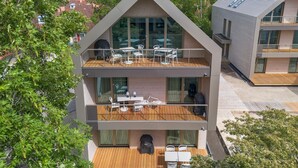A modern two-story building with a wooden deck, outdoor seating, and large windows. - 1 bedroom stunning apartment in Tossens (Tossens)
