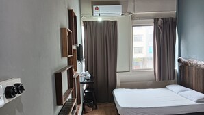 A hotel room with two beds, a wooden floor, a TV mounted on the wall, and a window with curtains. - Hotel O Hi Inn 2 (Sibu)