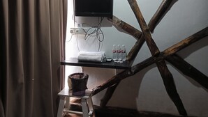 A room with a wooden chair, a small table with a TV, a power strip, and bottled water. - Hotel O Hi Inn 2 (Sibu)
