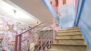 A staircase with a pink railing and a wall decorated with cartoon characters.