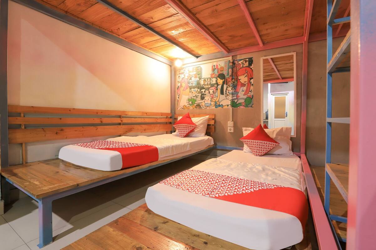A room with two beds, wooden benches, and a mural on the wall.