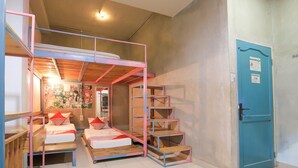 A room with bunk beds, a blue door, and a mural on the wall.