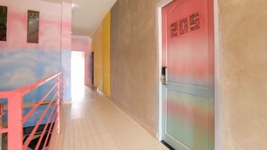 A hallway with a red door labeled "205" and a pink railing.