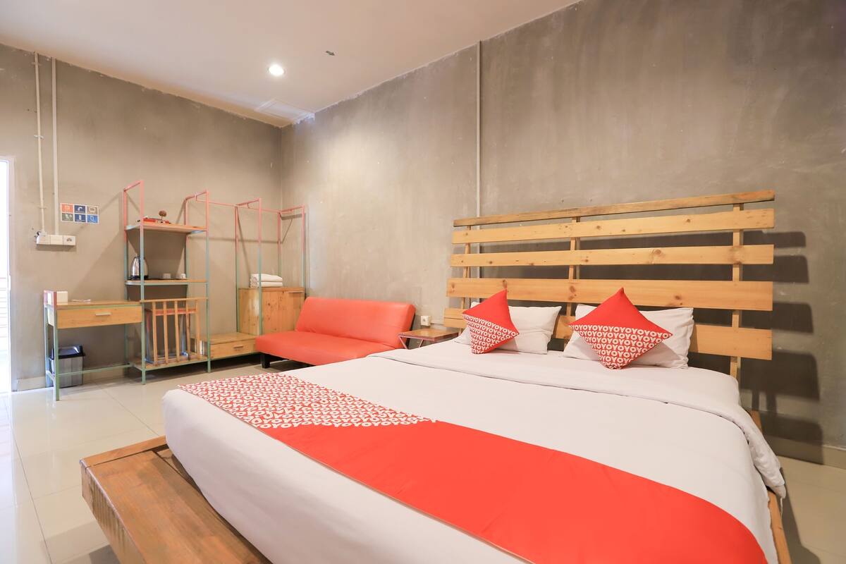 A modern bedroom with a large bed, a wooden headboard, and a desk with a chair.