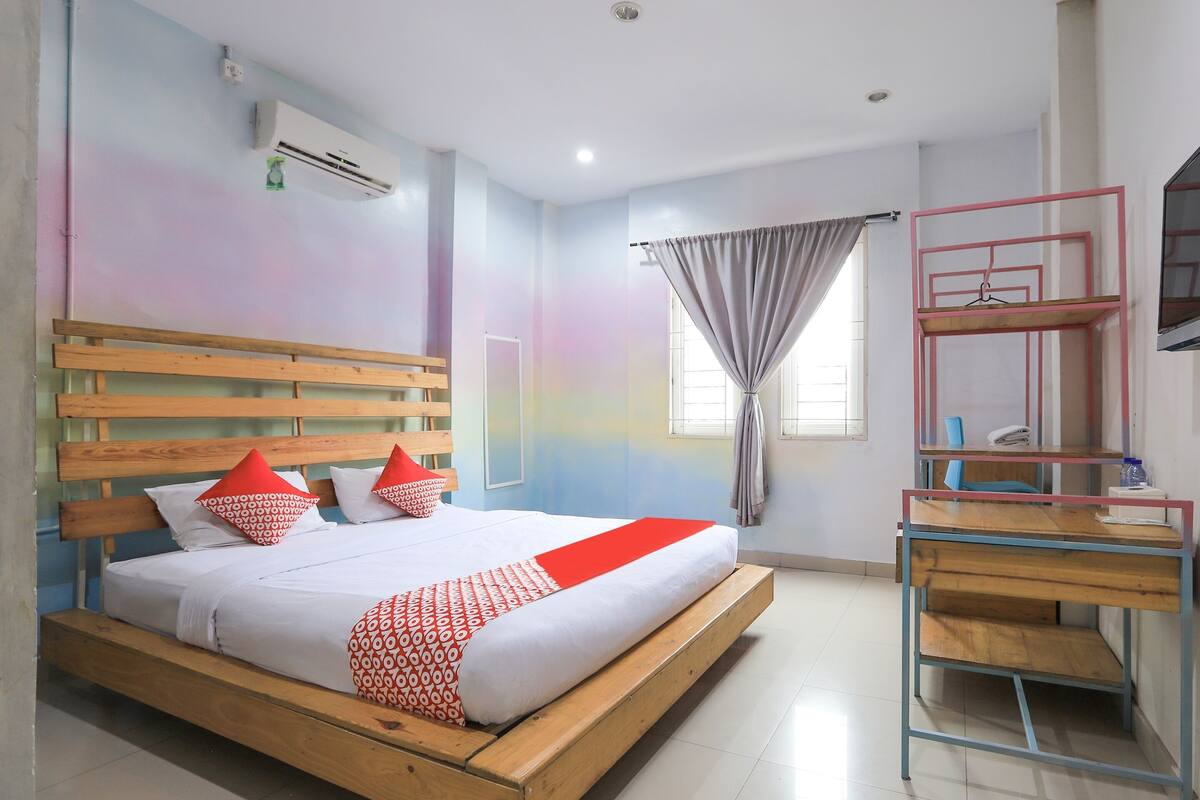 A bedroom with a wooden bed, a desk, and a TV mounted on the wall.