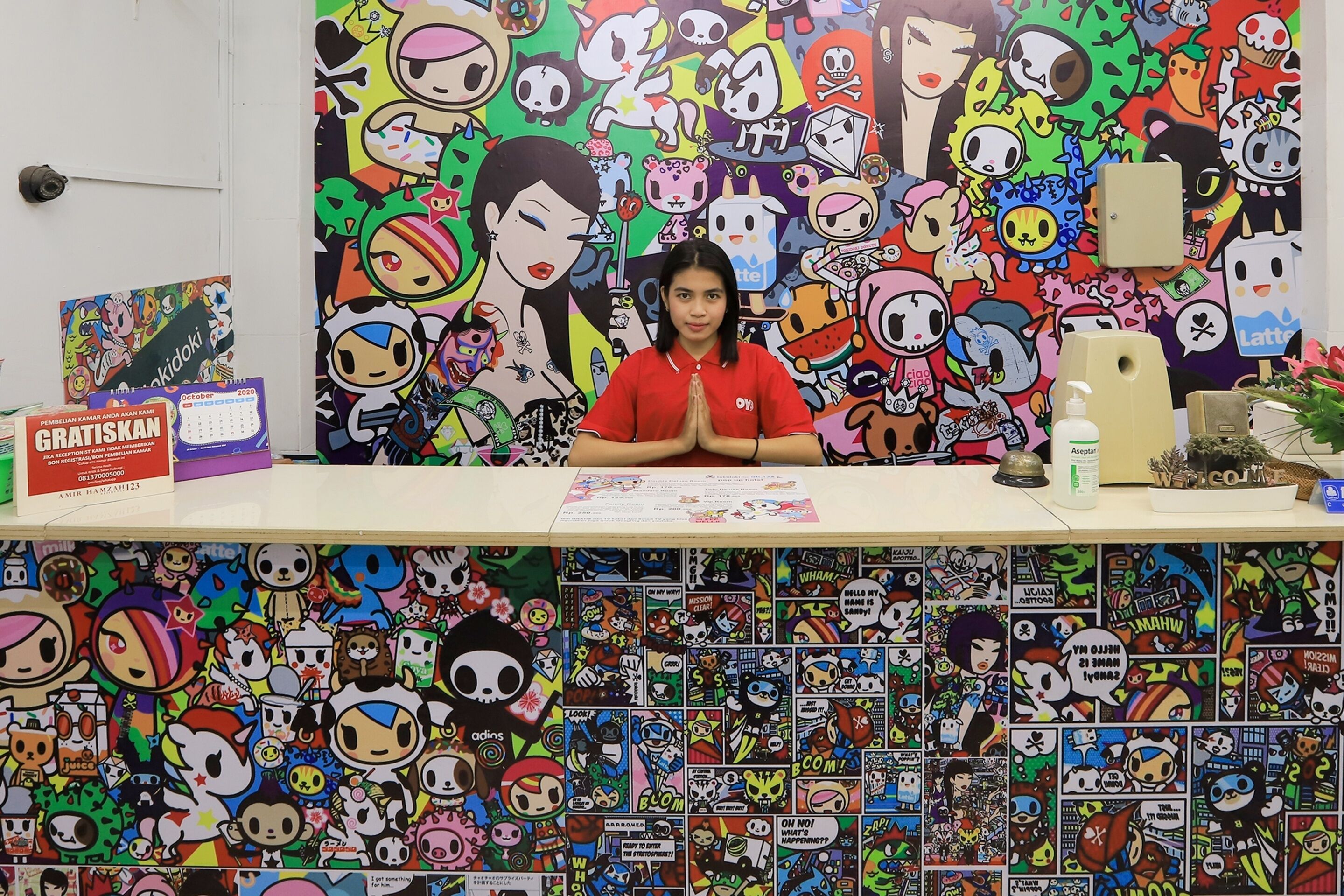 A desk with a colorful cartoon-themed backdrop, a calendar, and a small plant.
