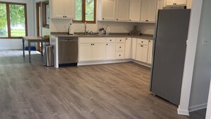 Una cocina amplia con armarios blancos, un refrigerador de acero inoxidable y una mesa de comedor de madera.