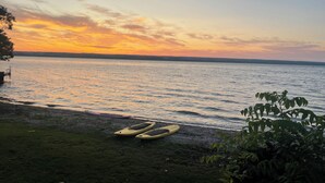 Una vista del atardecer sobre un cuerpo de agua tranquilo con kayaks en la orilla.