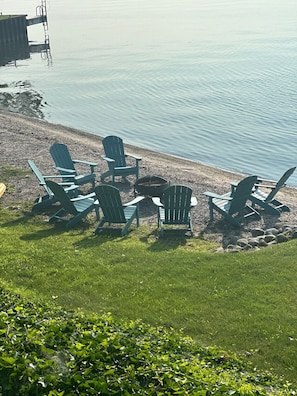Ein Sitzbereich am Seeufer mit Adirondack-Stühlen und einer Feuerstelle.