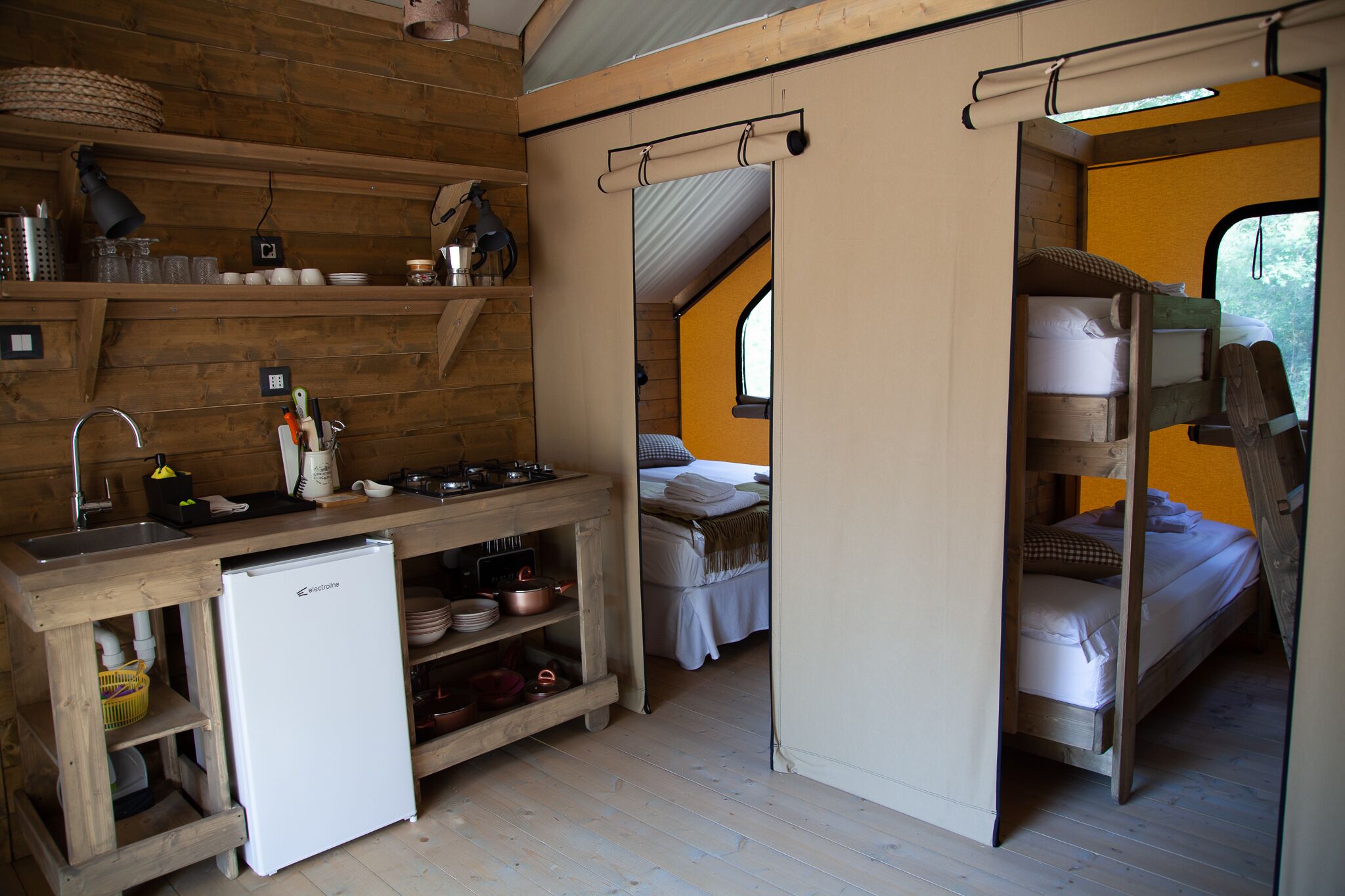 Una habitación compacta de estilo rústico con kitchenette, una cama litera y un ventanal pequeño.