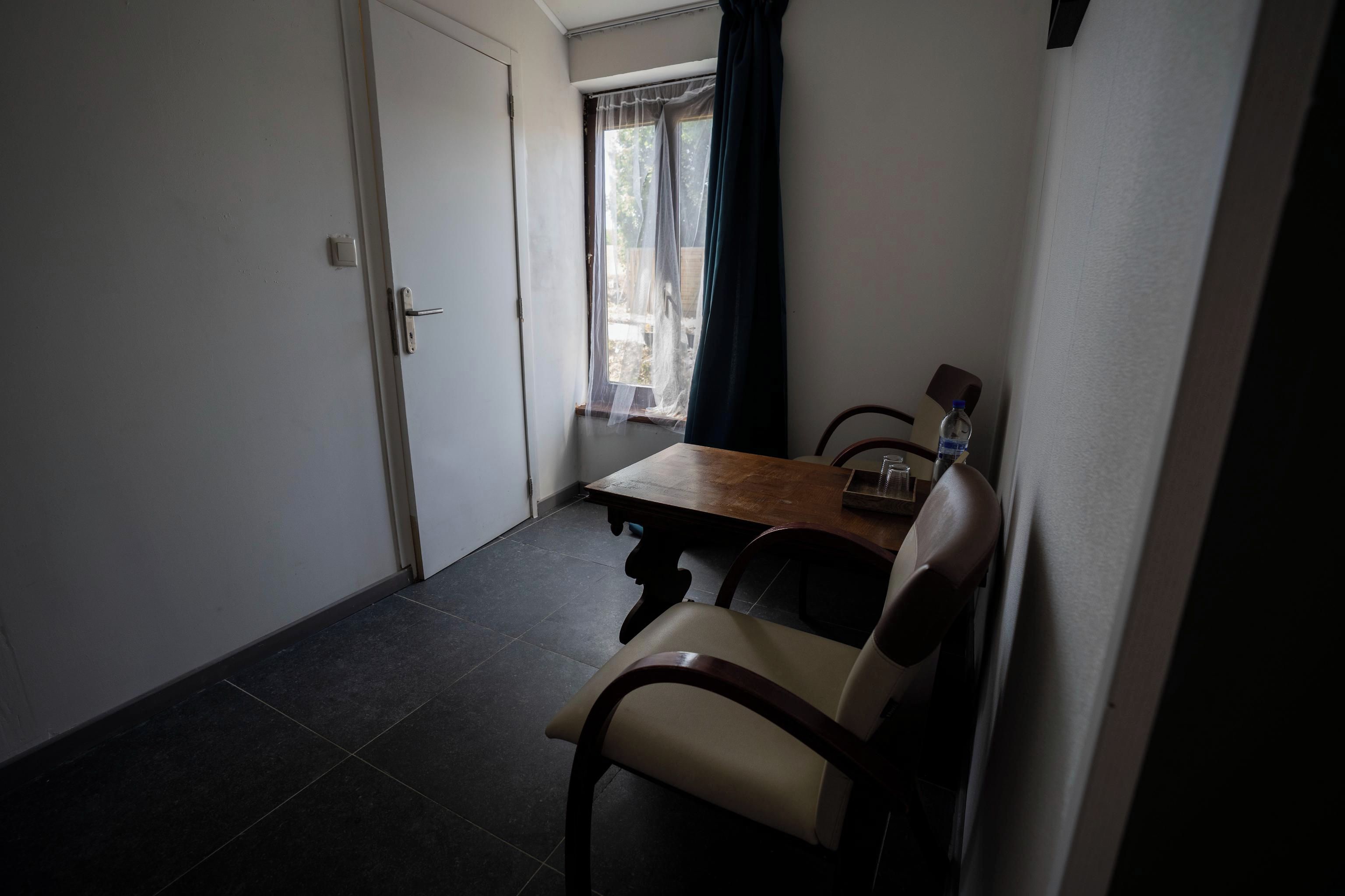 A small dining area with a table and chairs, a window with curtains, and a door.