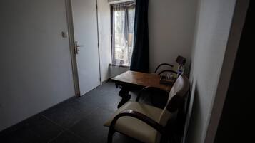 A small dining area with a table and chairs, a window with curtains, and a door.