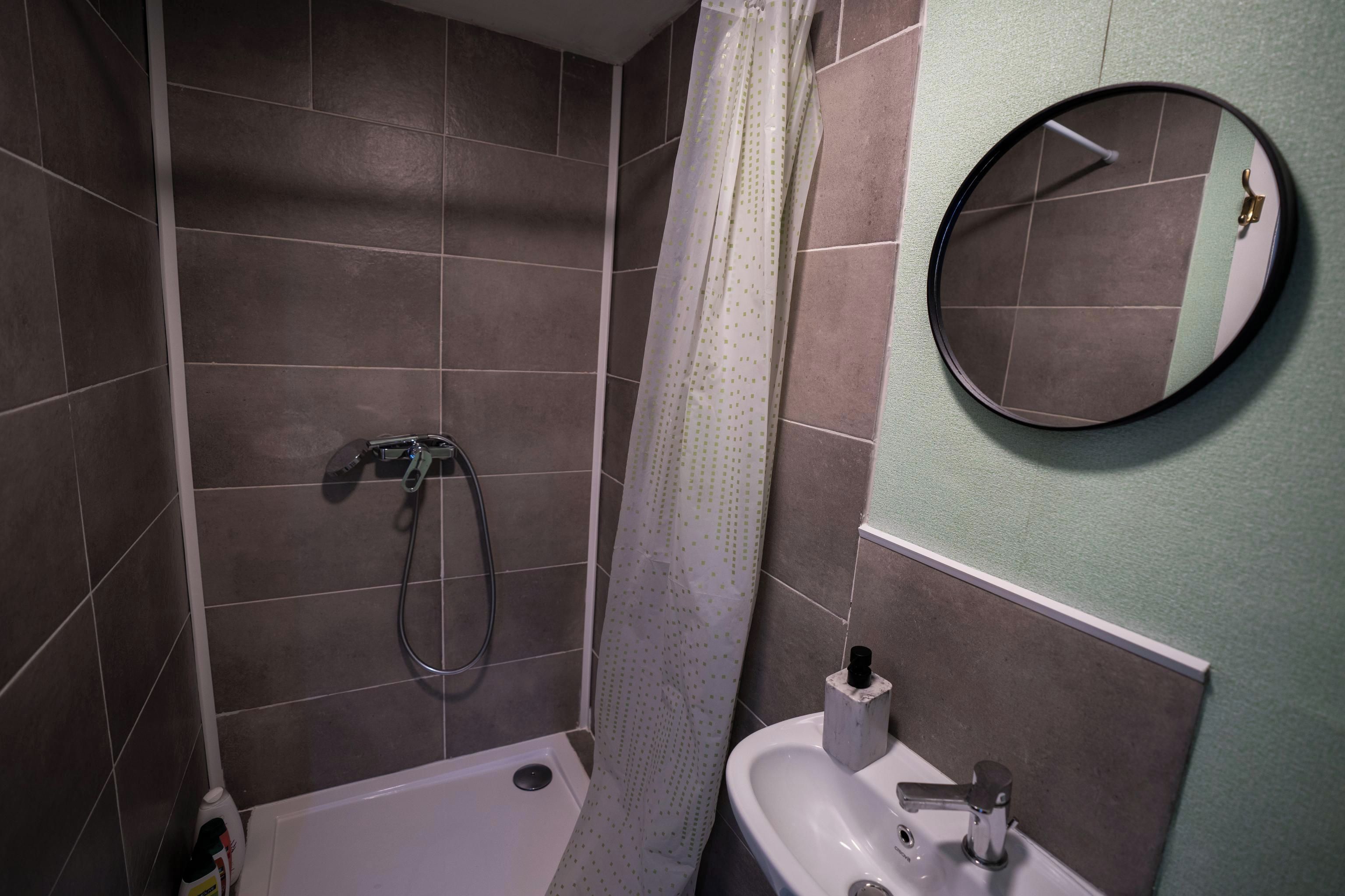 Une salle de bain avec une douche, un lavabo et un miroir.