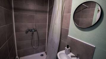 Une salle de bain avec une douche, un lavabo et un miroir.