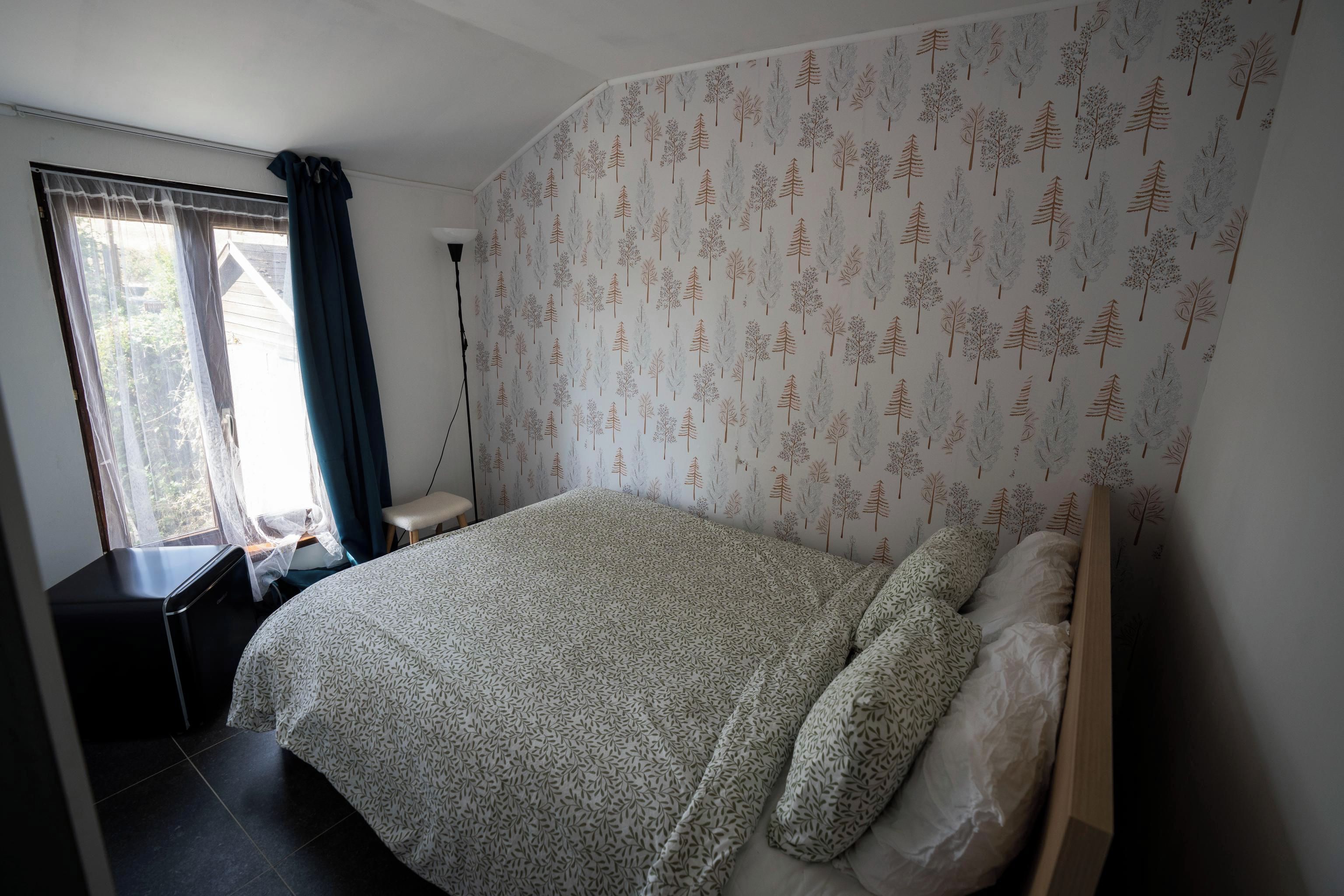 Un dormitorio con cama, escritorio y ventana con cortinas.