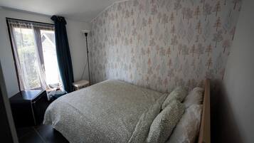 Un dormitorio con cama, escritorio y ventana con cortinas.