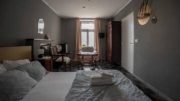 A hotel room with a bed, a desk, a chair, a table, and a wardrobe.