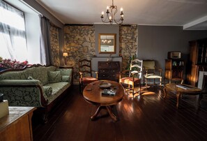 Ein gemütliches Wohnzimmer mit Steinwand, einer Kandelaber, einer Couch, einem Couchtisch und einem Bücherregal.