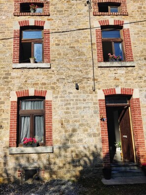 Ein mehrgeschossiges Gebäude mit Ziegelwänden und zahlreichen Fenstern, einige mit Fensterläden.