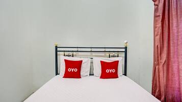 A bed with a white mattress and two red pillows with the word "OYO" on them.