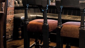 A traditional interior with a wooden bench, a brick wall, and a wooden door. - Lower Turks Head  (Manchester)
