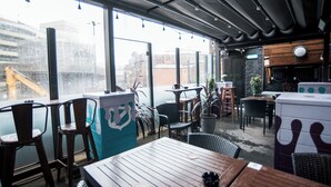 An indoor seating area with tables and chairs, large windows, and a view of the cityscape. - Lower Turks Head  (Manchester)
