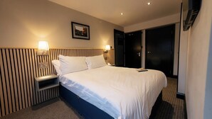 A hotel room with a large bed, two bedside tables with lamps, a wall-mounted picture, and a wardrobe. - Lower Turks Head  (Manchester)