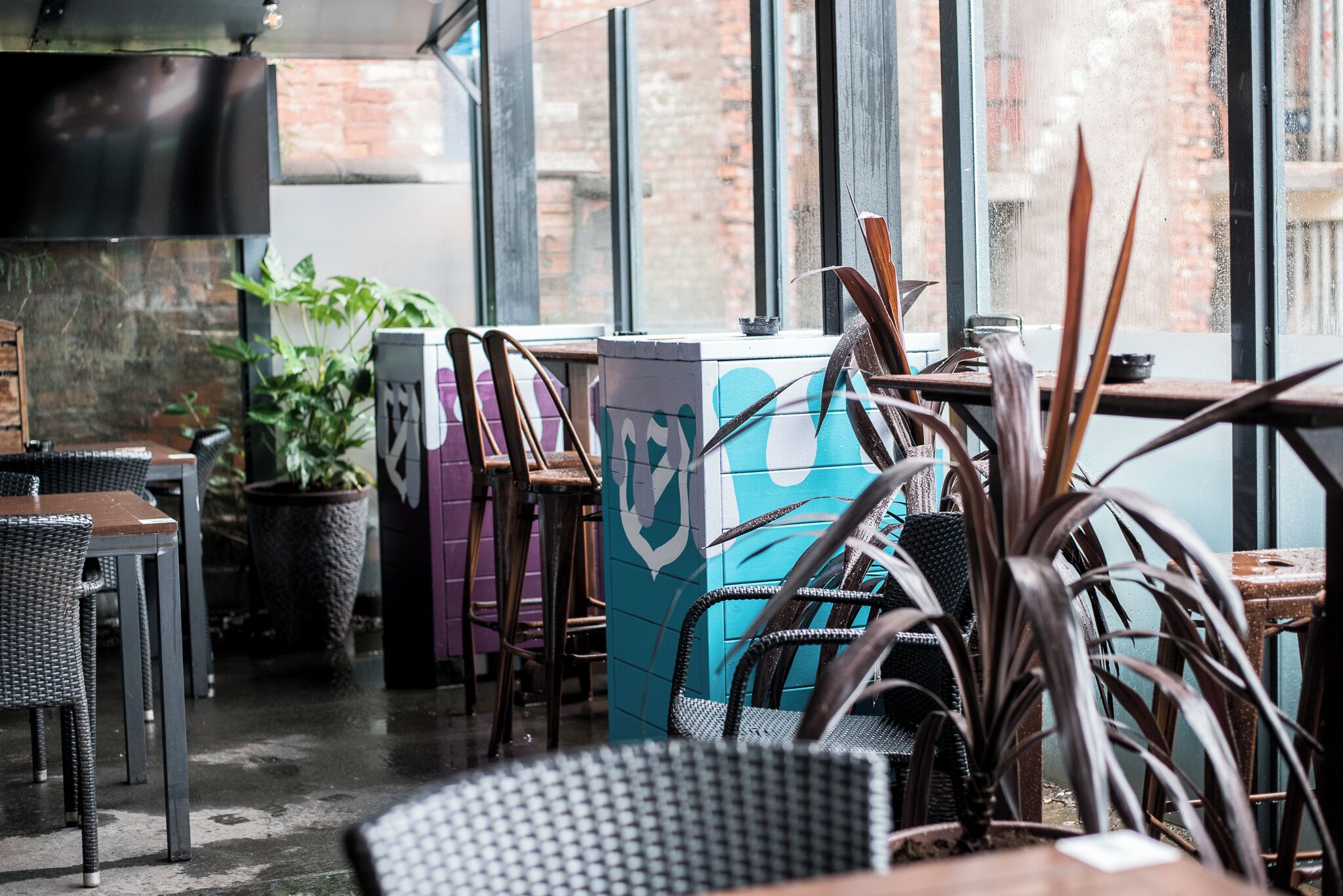 Un restaurant doté d’une terrasse, de plantes en pot et d’un mur de briques en arrière-plan.
