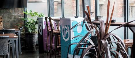 Un restaurant doté d’une terrasse, de plantes en pot et d’un mur de briques en arrière-plan.