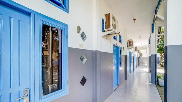 A hallway with blue doors and white walls, air conditioning units, and a tiled floor. - Hotel O Anugrah (Kualuh Hulu)