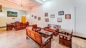 A spacious room with wooden furniture, including sofas and a table, and a chandelier. - Hotel O Anugrah (Kualuh Hulu)