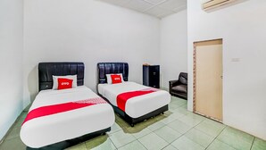 A hotel room with two beds, each with a black headboard and red bedding accents. There is a wooden door and a black speaker in the room. - Hotel O Anugrah (Kualuh Hulu)