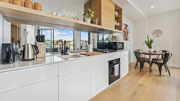 A modern kitchen with white cabinetry, a wooden countertop, and a dining area with a table and chairs.
