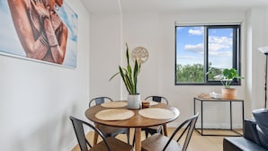A dining area with a round wooden table, black chairs, and a potted plant.