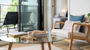 A modern living room with a glass coffee table, a sofa with cushions, and a chair.