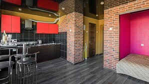 A modern kitchen with red cabinets, a brick fireplace, and a bar area with stools. - Elegant Apartment in Minsk (Minsk)