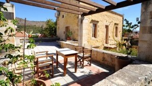 Une terrasse extérieure rustique, avec des meubles en bois et un mur en pierre.