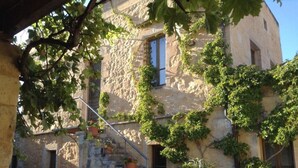 Un bâtiment rustique en pierre, avec des murs couverts de lierre, un escalier en bois et des plantes en pot.