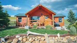 A log cabin with a porch, a dining area, and a grill outside.