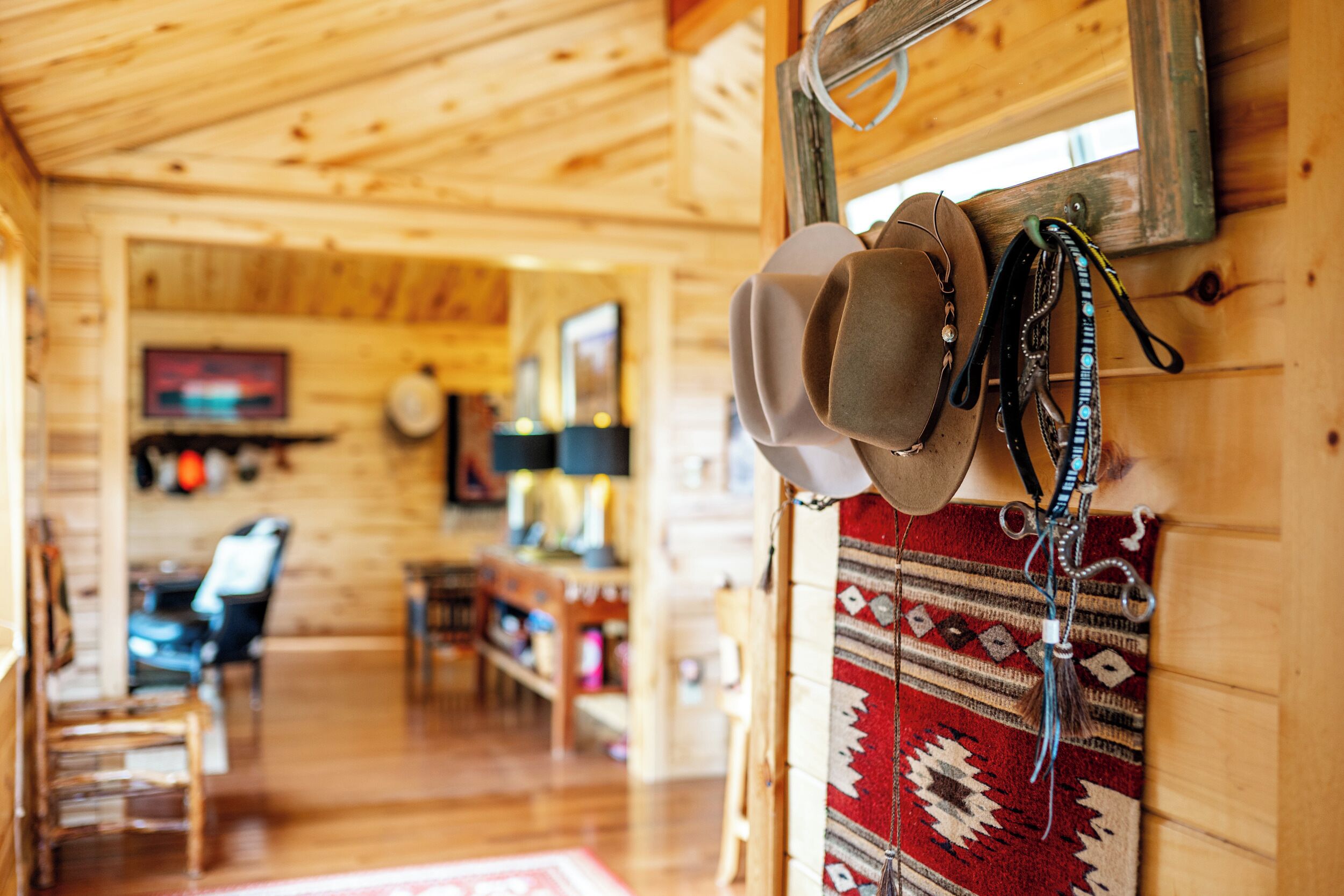 Un intérieur chaleureux avec des murs en bois, un tapis à motifs et un porte-chapeaux garni de chapeaux.