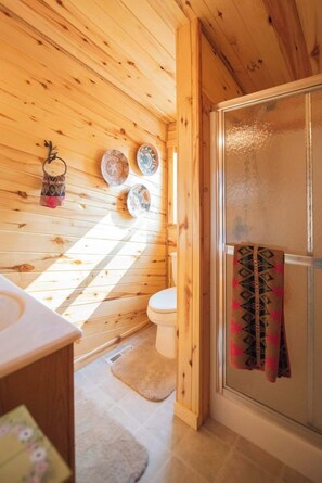 Un intérieur en bois comprenant des toilettes, un lavabo et une porte de douche en verre.