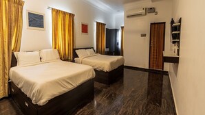 Ein Hotelzimmer mit zwei Betten, einem Deckenventilator, einer Klimaanlage und einem Fernseher.